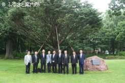 記念樹を前に記念写真に納まる式典･祝賀会に出席した歴代の場長