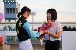 元騎手の鈴木麻優さんから、女性騎手として現役を続ける藤田菜七子騎手に、花束が渡された
