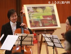 高沢葉子氏の競馬場の絵を背景に演奏する「ノンノン・マリア」