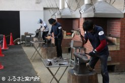 燃え上がるコークスの炎を背に蹄鉄作製に取り組む選手達
