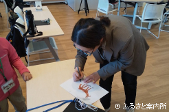 キッズが描いた馬の絵にサインをする高草木こぶ氏